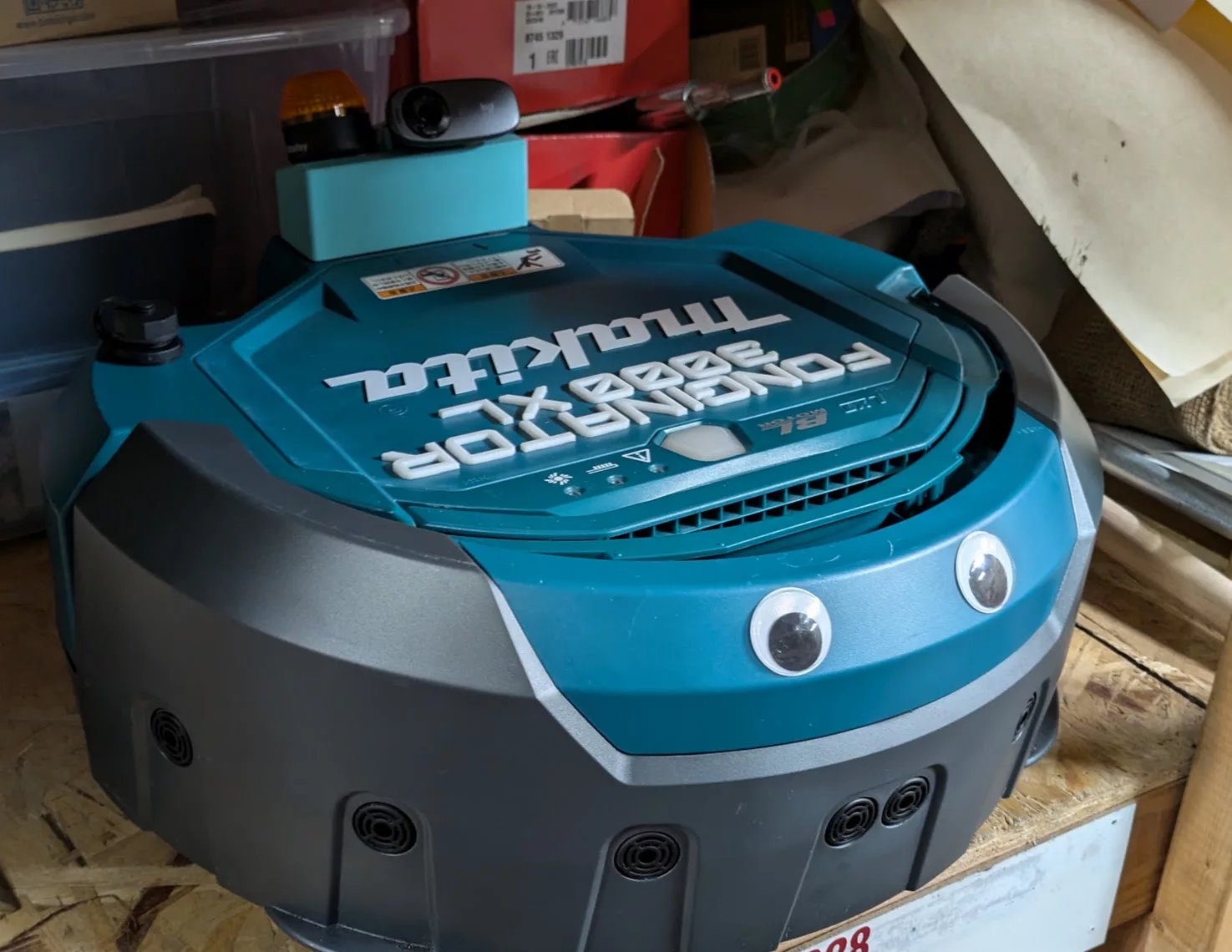 Makita robot vacuum with googly eyes and a webcam on top